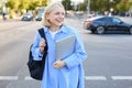 Lifestyle portrait of candid young woman, walking on street, laughing and smiling, holding backpack and laptop, looking