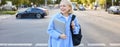 Lifestyle portrait of candid young woman, walking on street, laughing and smiling, holding backpack and laptop, looking Royalty Free Stock Photo