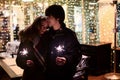 Lifestyle portrait of couple in love holding sparkling New Year fireworks on the city streets with lot of lights on background. Royalty Free Stock Photo