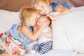 Caucasian girls sisters holding kissing little baby, sitting on bed Royalty Free Stock Photo