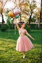 lifestyle portrait of elegant ballerina in a pink silk dress and white pointe shoes balancing on tiptoe on one leg and Royalty Free Stock Photo