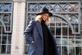 Lifestyle portrait of fashionable woman wearing winter or spring outfit, felt hat, gray wool coat and turtleneck. Outdoors. Female