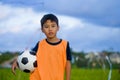 Lifestyle portrait of handsome and happy young boy holding soccer ball playing football outdoors at green grass field smiling chee Royalty Free Stock Photo