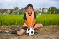 Lifestyle portrait of handsome and happy young boy holding soccer ball playing football outdoors at green grass field smiling chee Royalty Free Stock Photo