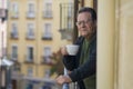 Lifestyle portrait of happy and cheerful mature man 65 to 70 years old at home balcony feeling positive and relaxed drinking