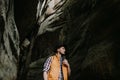 Lifestyle Portrait of a hipster traveler in a hat and with a backpack in a mountain cave