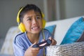 Lifestyle portrait of young latin little kid excited and happy playing video game online with headphones holding controller enjoyi Royalty Free Stock Photo