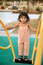 Lifestyle portrait of little toddler girl in jumpsuit at the playgroung in the summer, childhood memories concept