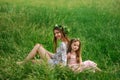 Lifestyle portrait mom and daughter are sitting on grass in the