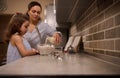 Lifestyle portrait of a mom pouring milk into bowl of flour and mixing ingredients with a whisk to prepare pancake dough. Mother Royalty Free Stock Photo