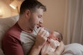 Lifestyle portrait of proud happy man holding tenderly bottle feeding her child - an adorable and beautiful newborn baby girl in Royalty Free Stock Photo