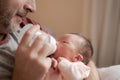 Lifestyle portrait of proud happy man holding tenderly bottle feeding her child - an adorable and beautiful newborn baby girl in Royalty Free Stock Photo