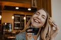 Lifestyle Portrait of smiling young casual blonde woman eating a cookie and drinking coffee, tea in cafe. Happy girl eating a Royalty Free Stock Photo