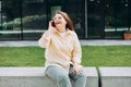 Lifestyle portrait of a stylish young 30s businesswoman talking on cell phone, making call and standing on modern city Royalty Free Stock Photo