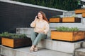 Lifestyle portrait of a stylish young 30s businesswoman talking on cell phone, making call and standing on modern city Royalty Free Stock Photo