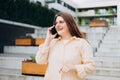 Lifestyle portrait of a stylish young 30s businesswoman talking on cell phone, making call and standing on modern city Royalty Free Stock Photo