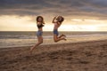 Lifestyle portrait of two happy and attractive young Asian Korean women girlfriends jumping on sunset beach excited and cheerful e Royalty Free Stock Photo