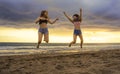 Lifestyle portrait of two happy and attractive young Asian Korean women girlfriends jumping on sunset beach excited and cheerful e Royalty Free Stock Photo