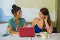 Young happy and beautiful caucasian and latin women working at office cafe with laptop computer discussing as digital business Royalty Free Stock Photo