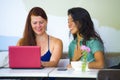 Young happy and beautiful caucasian and latin women working at office cafe with laptop computer discussing as digital business Royalty Free Stock Photo