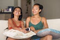 Lifestyle portrait of two young happy and relaxed Asian girlfriends having fun talking laughing and gossiping at home sofa couch s Royalty Free Stock Photo
