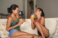 Lifestyle portrait of two young happy and relaxed Asian girlfriends having fun talking laughing and gossiping at home sofa couch s