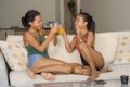 Lifestyle portrait of two young happy and relaxed Asian girlfriends having fun talking laughing and gossiping at home sofa couch s Royalty Free Stock Photo