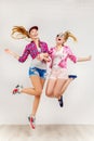 Lifestyle portrait of two young hipster girls best friends jump in studio Royalty Free Stock Photo