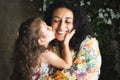 A lifestyle portrait of a white Caucasian mother and daughter embracing as the small girl gives her mom a kiss Royalty Free Stock Photo