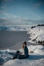 Lifestyle portrait of woman cuddled up in blanket posing in snow on an amazing sunny winter day in Scandinavia.