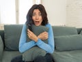 Portrait of a young woman looking scared and shocked watching scary movie on TV Royalty Free Stock Photo