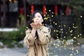 Lifestyle Portrait of young asian woman with brunette hair blowing golden confetti outdoor. Person celebrating birthday Royalty Free Stock Photo