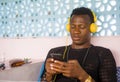 Lifestyle portrait of young attractive and cool hipster black afro American man using mobile phone and headset networking on Royalty Free Stock Photo