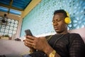 Lifestyle portrait of young attractive and cool hipster black afro American man using mobile phone and headset networking on Royalty Free Stock Photo