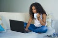 Young attractive and relaxed afro American student woman sitting at home sofa couch networking with laptop computer drinking coffe Royalty Free Stock Photo
