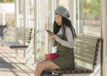 Lifestyle portrait of young attractive and relaxed Asian Chinese woman sitting on bench at train station platform waiting using Royalty Free Stock Photo
