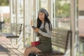 Lifestyle portrait of young attractive and relaxed Asian Japanese woman sitting on bench at train station platform waiting using Royalty Free Stock Photo
