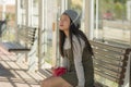 Lifestyle portrait of young attractive and relaxed Asian Korean woman sitting on bench at train station platform waiting cheerful Royalty Free Stock Photo