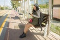 Lifestyle portrait of young attractive and relaxed Asian Korean woman sitting on bench at train station platform waiting using Royalty Free Stock Photo