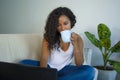 Young attractive and relaxed black afro American student woman sitting at home sofa couch networking with laptop computer drinking Royalty Free Stock Photo