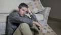 Lifestyle portrait young attractive sad and depressed man sitting on living room floor feeling desperate and stressed suffering Royalty Free Stock Photo