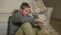 Lifestyle portrait young attractive sad and depressed man sitting on living room floor feeling desperate and stressed suffering Royalty Free Stock Photo