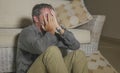 Lifestyle portrait young attractive sad and depressed man sitting on living room floor feeling desperate and stressed suffering