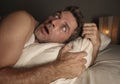 Lifestyle portrait of young attractive scared and paranoid man lying in bed having  bad dreams and nightmares looking around in Royalty Free Stock Photo