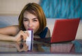 Lifestyle portrait of young attractive and upset woman at home couch checking finance with credit card and laptop computer worried Royalty Free Stock Photo