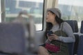 Lifestyle portrait of young beautiful and attractive Asian Japanese woman in winter hat looking thoughtful through window on train Royalty Free Stock Photo