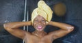 Lifestyle portrait of young beautiful black African American woman having a shower with her head wrapped in a towel smiling Royalty Free Stock Photo