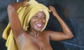 Lifestyle portrait of young beautiful black African American woman having a shower with her head wrapped in a towel smiling Royalty Free Stock Photo