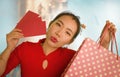 Lifestyle portrait of young beautiful and happy Asian Chinese woman holding Chinese New year red pockets and shopping bags at Royalty Free Stock Photo