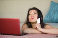 Lifestyle portrait of young beautiful and happy Asian Chinese woman holding credit card banking and online shopping with laptop co Royalty Free Stock Photo
